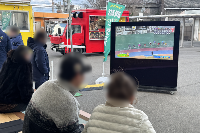 足元を温めながら、大型モニターに映し出されるレース映像を通じて競輪観戦を楽しむ様子